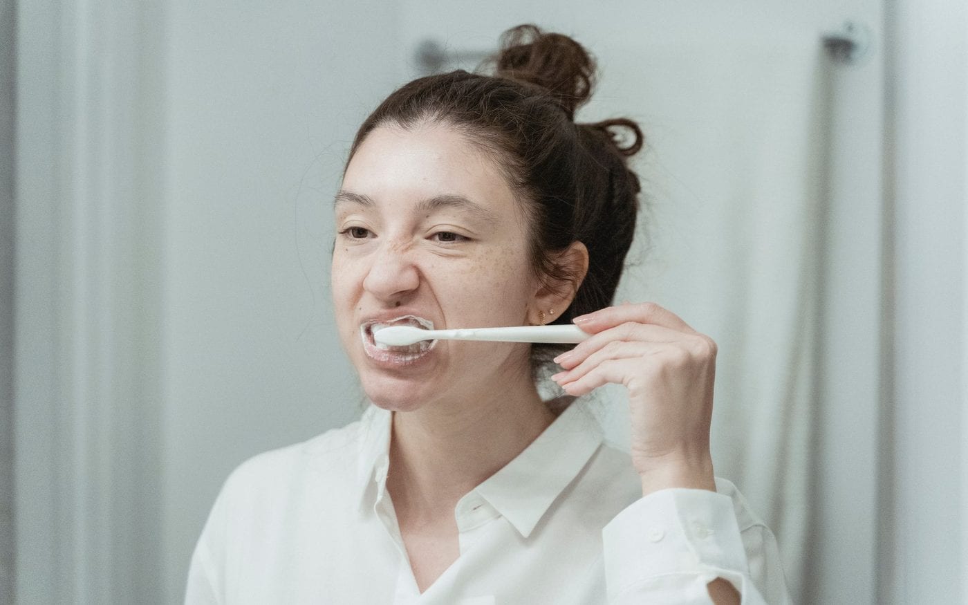 Woman brushing her teeth at a bathroom mirror