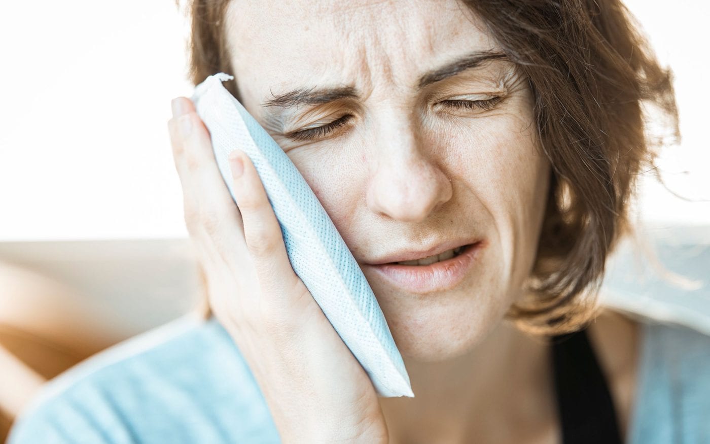 Woman holding a cold compress against her cheek for tooth pain
